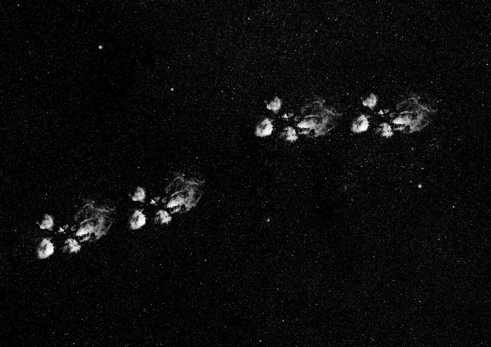 NGC 6334, the Cat's Paw Nebula, located 5,500 light-years distant is a massive star-forming region. This monochrome composite isolates four stark, white emission features against a void. The high-contrast framing mimics a feline track, transforming a cosmic nursery into a minimalist, graphic imprint walking across the deep black background.