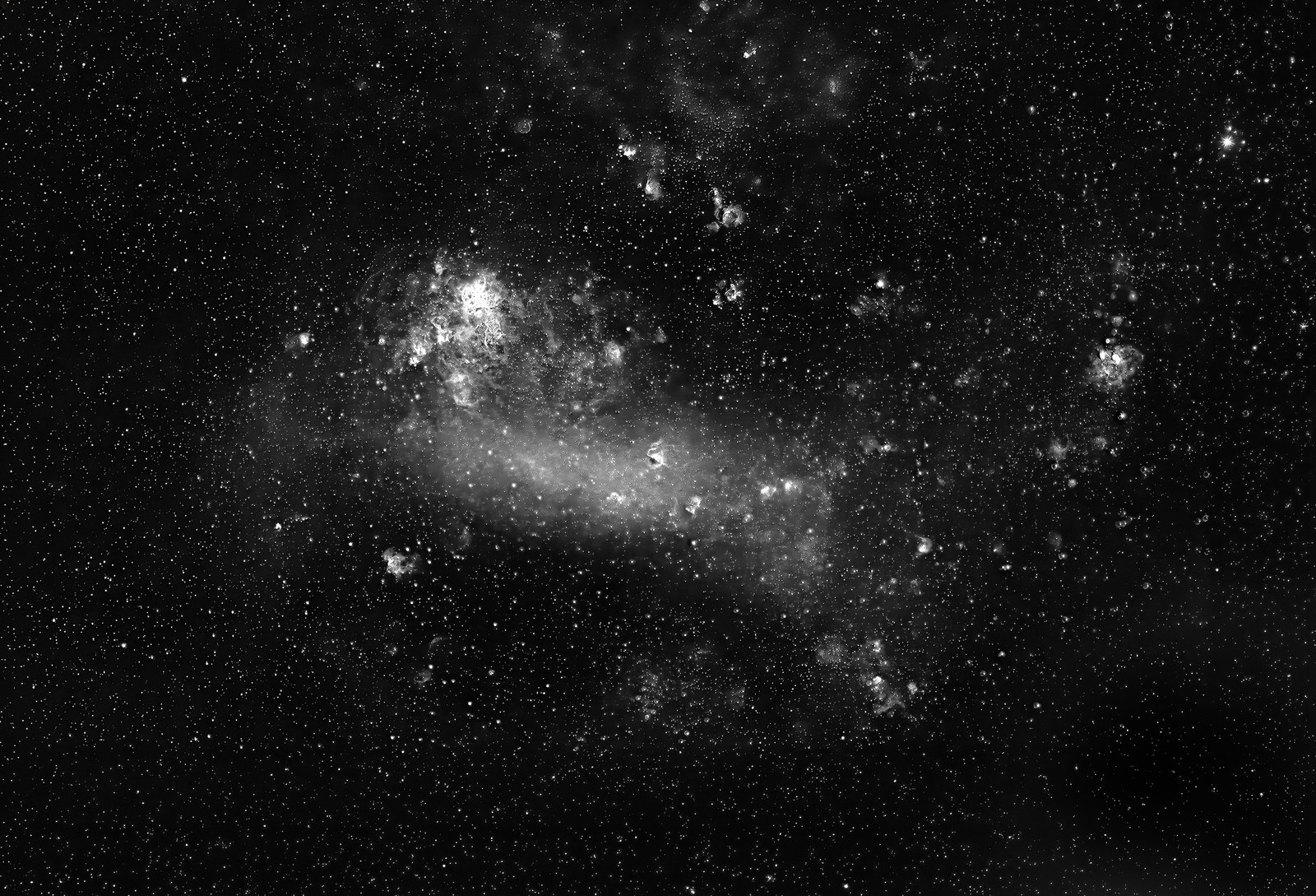 Our closest cosmic neighbor stripped down to its core elements. This monochrome presentation of the Large Magellanic Cloud (LMC) isolates the raw structural dynamics of this irregular satellite galaxy. By removing color, the central barred stellar structure and the churning hyperactive nurseries of the Tarantula Nebula (top left of LMC) stand out with exceptional clarity.