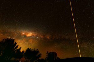 Piercing the heart of the galaxy. Looking straight up into the unpolluted night sky above Chile's Atacama Desert, a vibrant laser guide star beam fires from an off-screen dome, cutting directly across the dense dust lanes and starfields of the Southern Milky Way core to help correct for Earth's atmospheric distortion.